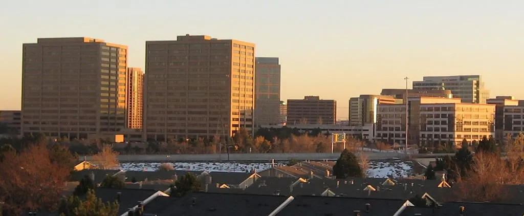 A peaceful afternoon in Greenwood Village, Colorado, with tree-lined streets and modern buildings, capturing the essence of suburban serenity.