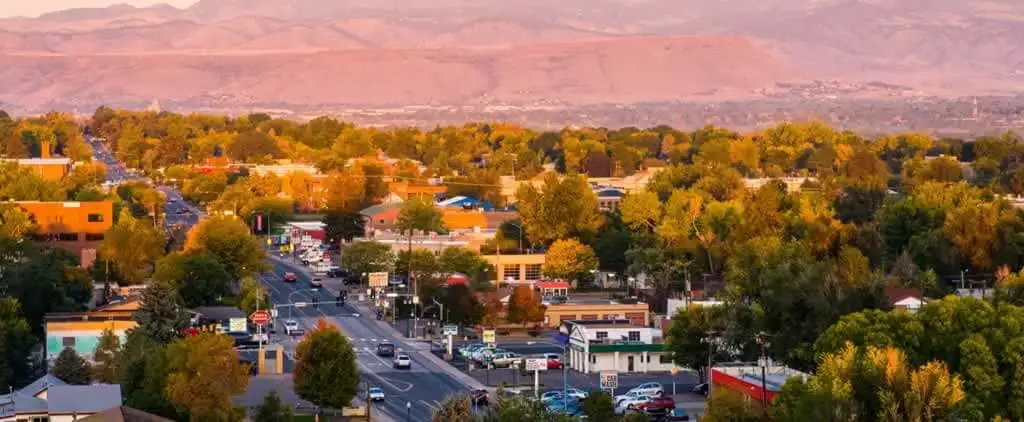 Professional movers arranging furniture and boxes into a moving van with the charming Wheat Ridge, Colorado neighborhood in the background.