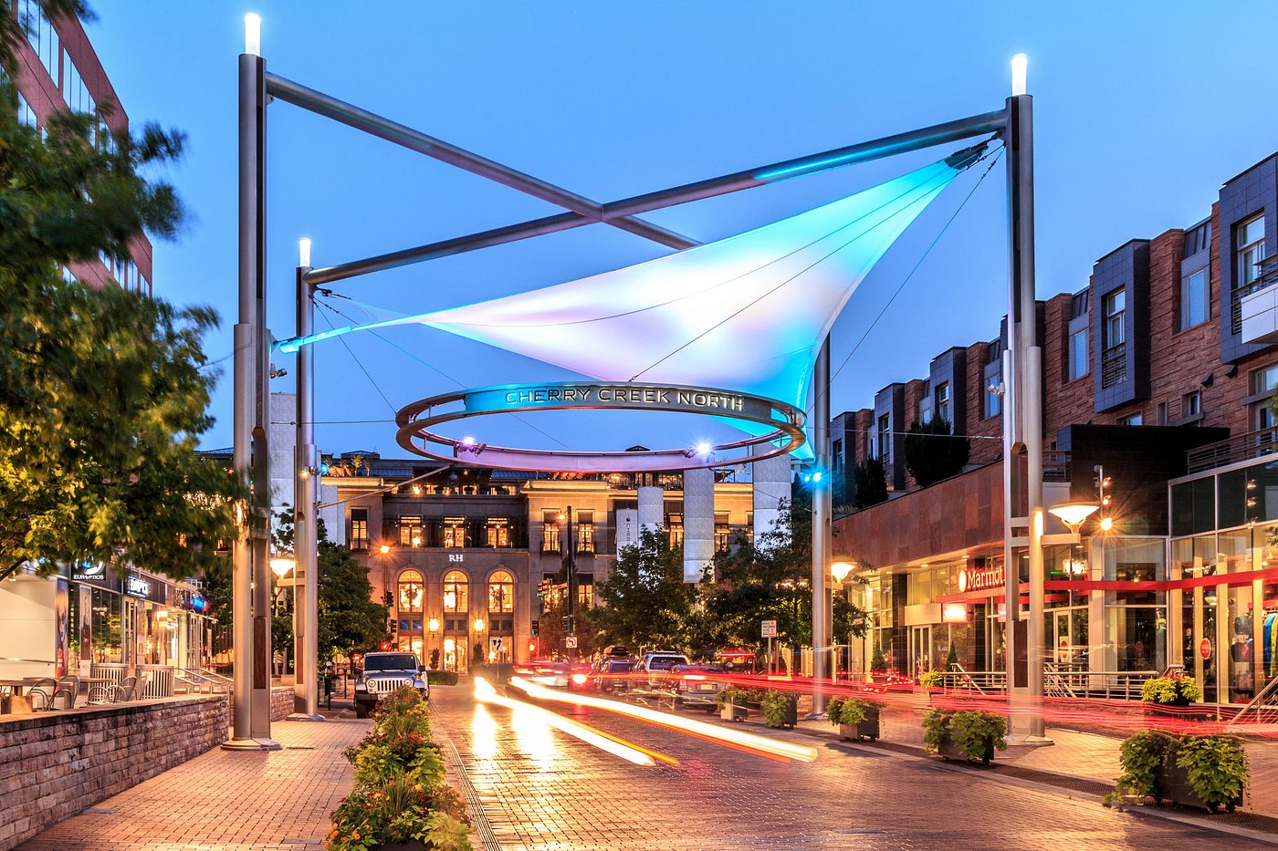 Cherry Creek North sign and lighted shade sail over a shopping street at dusk in Denver
